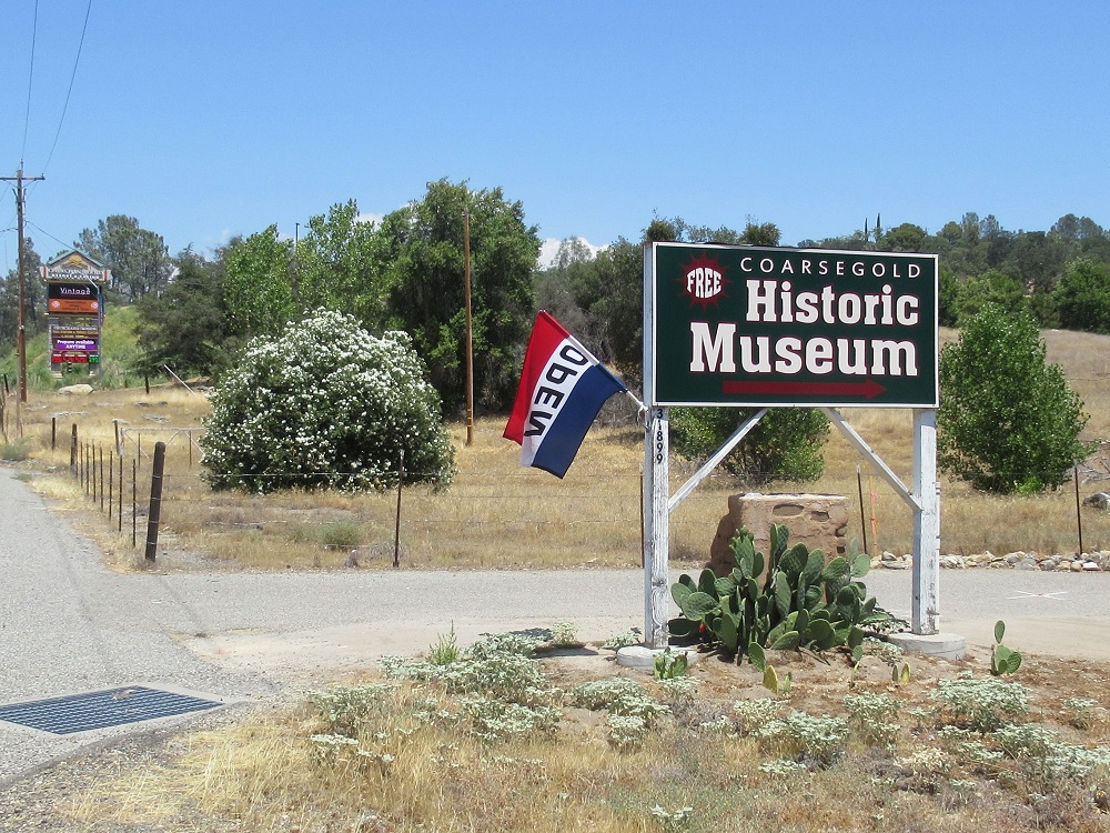 Photo of the Museum sign with the open flag flying. 